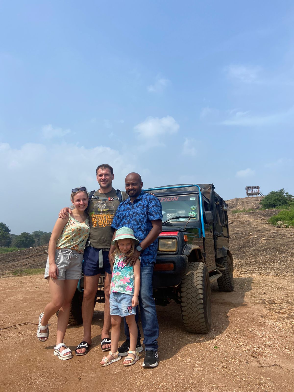 Travellers standing beside a safari vehicle