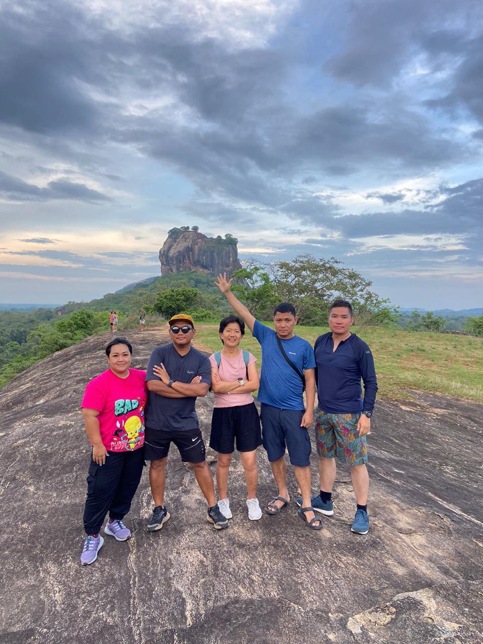 Travellers at a rocky viewpoint beneath a cloudy sky